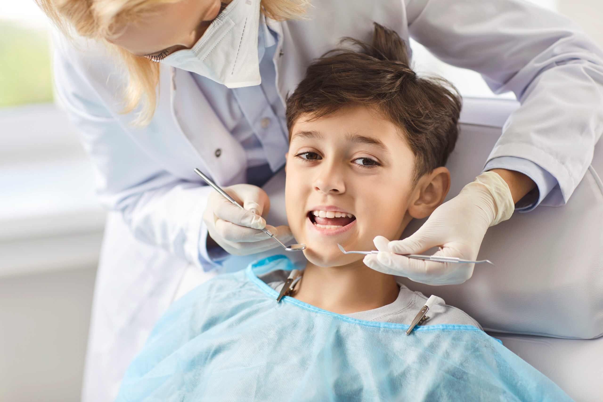 Dentist in the clinic examines a smiling boy, close-up. At the doctor, the child opened his mouth to examine his teeth. Concept dental health in adolescents, dental hygiene , tooth decay
