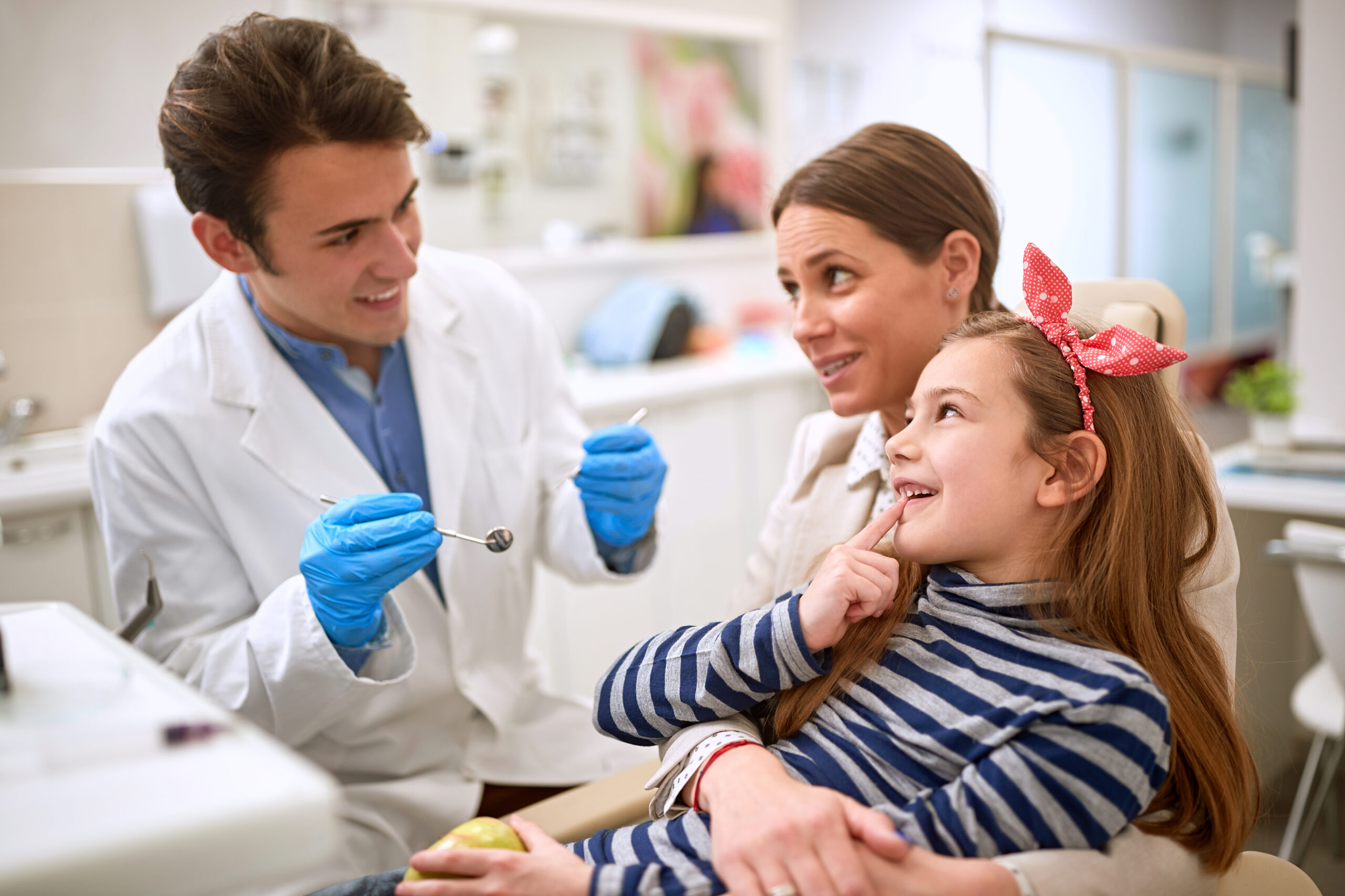 Litle female patient showing tooth to dentist