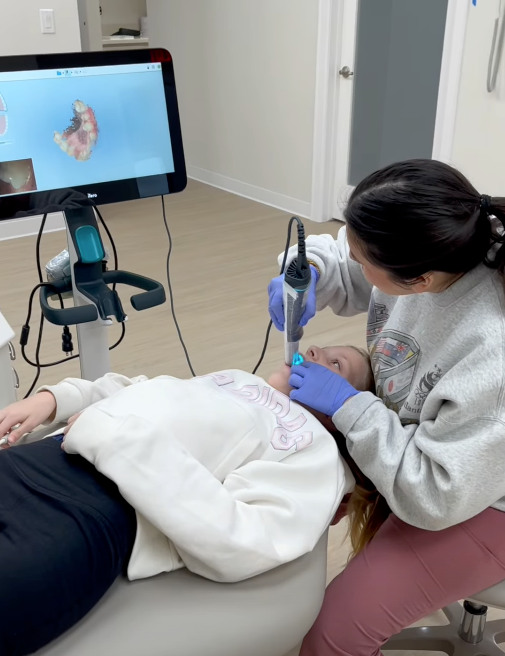 Dental assistant performing digital 3D intraoral scan for teen Invisalign patient