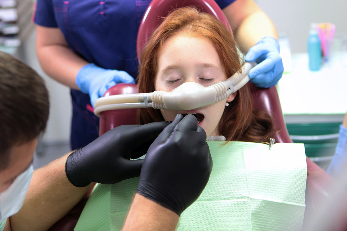 Little girl is being treated for teeth with anesthesia. Girl closed her eyes. Nitrous oxide for pain relief of child. Treatment of baby teeth.