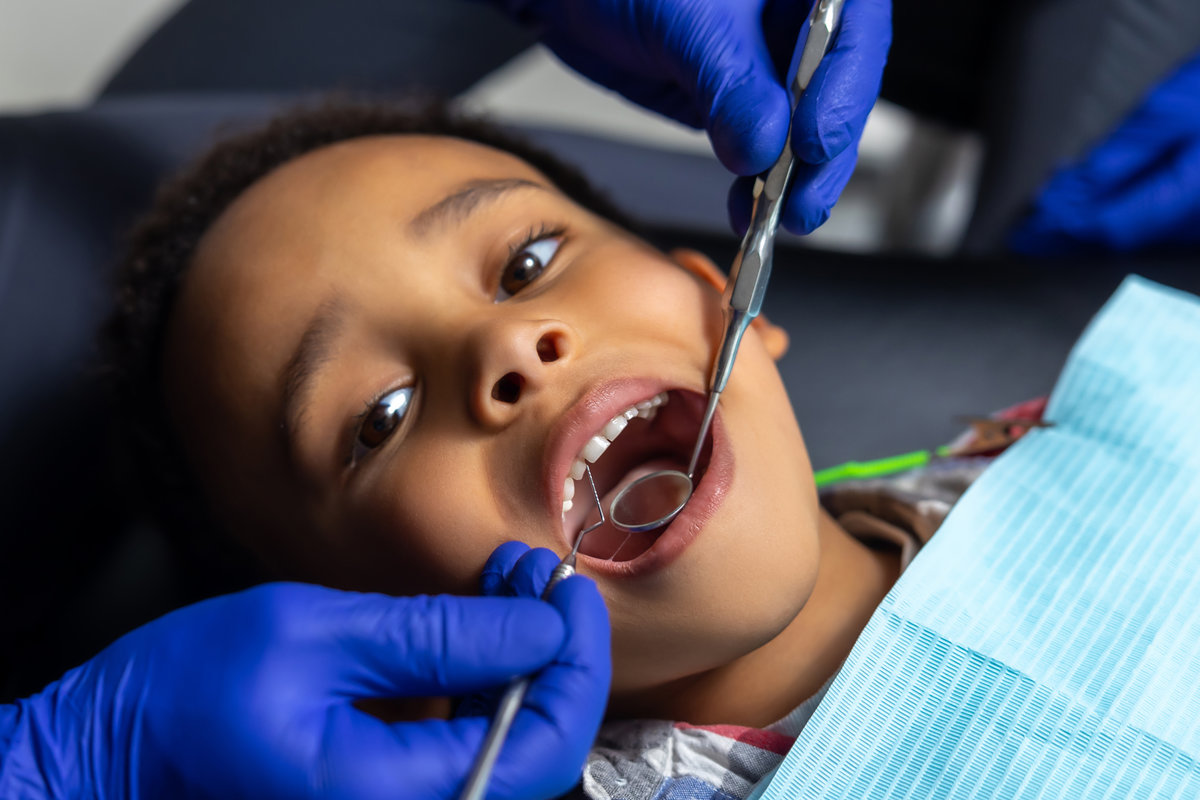 In dentistry. Dentist treating dark-skinned boys teeth